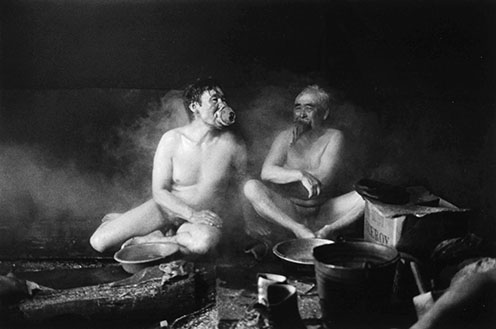 Blaise Tinker and Tom Tunutmoak in a firebath. Scammon Bay. The grass mothpieces filter the smoke.