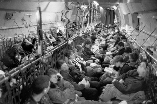 <p>In an Air Force C-141, 132 scientists and support staff make the 5 1/2 hour flight from New Zealand to McMurdo Station. Dressed in "extreme cold weather" gear, the women are seated in front so they can use the crew facilities under the flight deck. Men are in back so they can use the funnel behind the curtain.</p><p>“Just as the plane touched down you could look at all the people and see the excitement in their faces. I thought, ‘finally I’m getting to a continent before my father’.”<br/>—Anna Meade, hazardous waste specialist</p><p>“As soon as I heard about the place I wanted to come. But I didn’t want to know anything about it on the off chance that I wouldn’t make it here. It would be worse to know how amazing it was and not come. I’ve got a huge collection of books now.”</br>—Dr. Simon Hart</p>