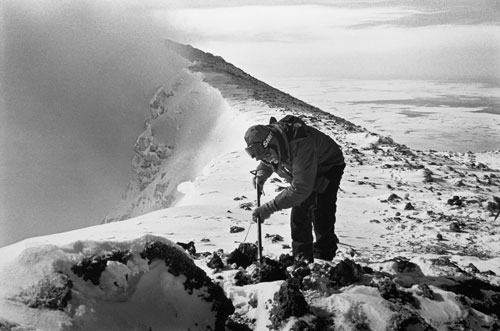<p>Volcanologist Michael O’Keefe examines the contents of a lava "bomb" at the 12,400 foot summit of Mt. Erebus.</p><p>"In 1984 the seismometers on the mountain were going wild. People on the other side of the Sound could see the bombs flying through the air in the night. Within thirty minutes after arriving on The Ice I was standing by the upper hut on Erebus. I walked just a few feet from the helicopter and there sitting on the ground was a lava bomb six feet across, smoldering. I jumped in the helo and said, ’Let’s get the hell out of here!’"<br/>—Dr. Philip Kyle</p>